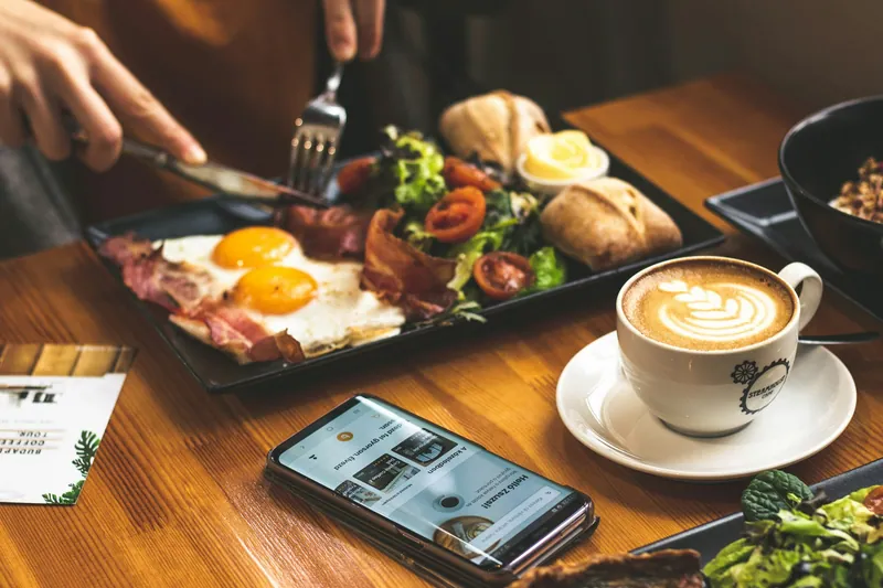 Frukost med kaffe, ägg och grönsaker på ett kafébord