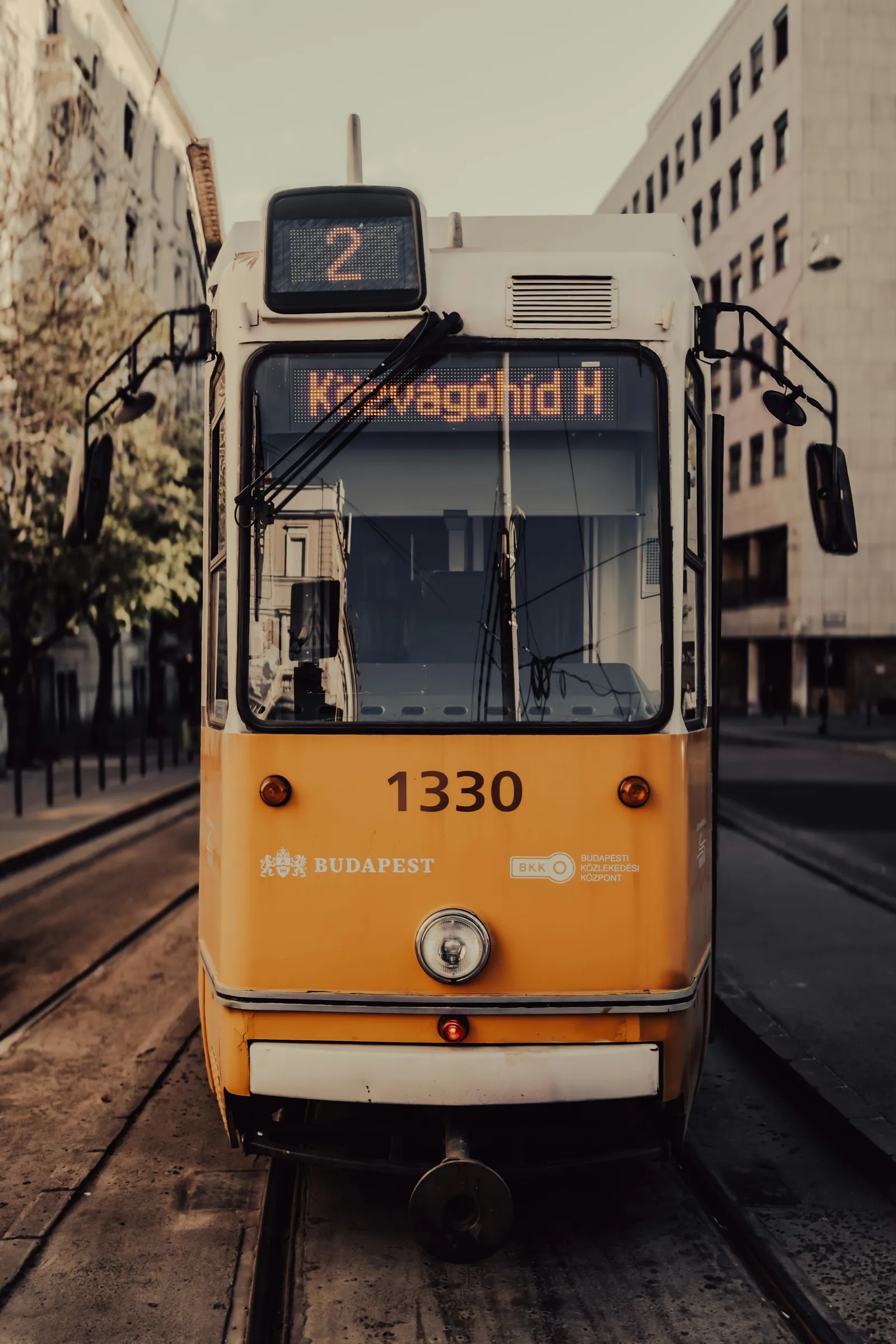 Gul spårvagn på spår i en gata i Budapest